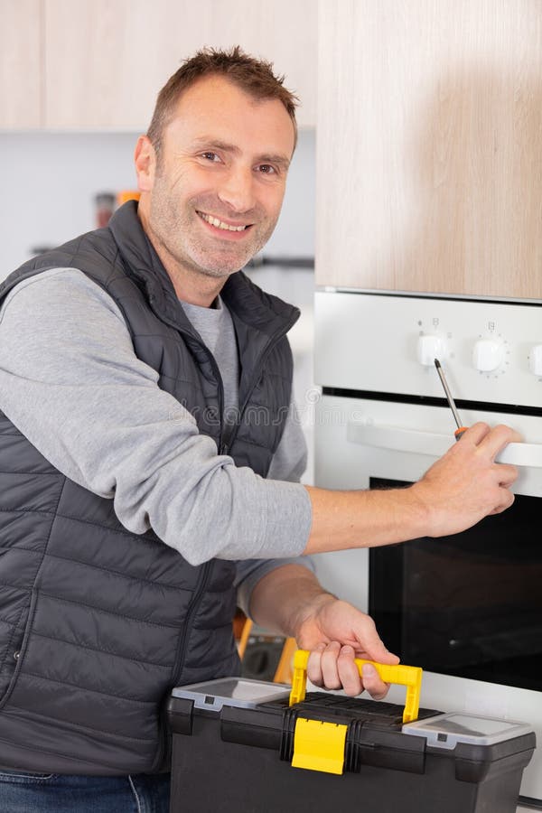 Repairman Examining Oven with Toolbox in Kitchen Stock Photo Image of