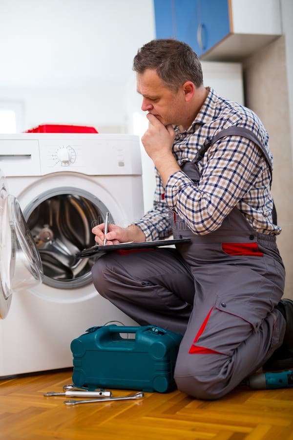 Repairman naprawia pralkę na białym tle zdjęcie stock