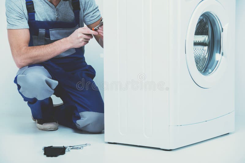 Repairman is Repairing a Washing Machine on the White Background Stock