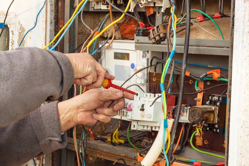 Reparación de la distribución de la electricidad en una casa vieja El hombre repara la centralita telefónica fotografía de archivo Reparación de la distribución de la electricidad en una casa vieja El hombre repara la centralita telefónica fotografía de archivo
