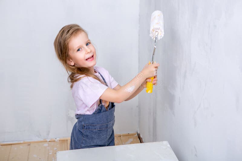Reparación en el apartamento La madre y la hija felices de la familia en delantales pintan la pared con la pintura blanca muchach imagen de archivo libre de regalías Reparación en el apartamento La madre y la hija felices de la familia en delantales pintan la pared con la pintura blanca muchach imagen de archivo libre de regalías