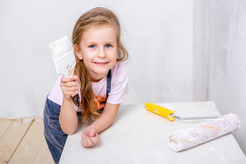 Reparatur in der Wohnung Glückliche Familienmutter und kleine Tochter in den blauen Schutzblechen malt die Wand mit weißer Farbe lizenzfreie stockfotografie Reparatur in der Wohnung Glückliche Familienmutter und kleine Tochter in den blauen Schutzblechen malt die Wand mit weißer Farbe lizenzfreie stockfotografie