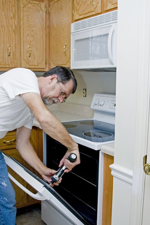 Repair man testing the operation of stove & oven found over door mis aligned. Repair man testing the operation of stove & oven found over door mis aligned