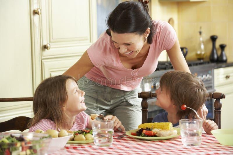 Repas de portion de mère aux enfants dans la cuisine photos stock Repas de portion de mère aux enfants dans la cuisine photos stock