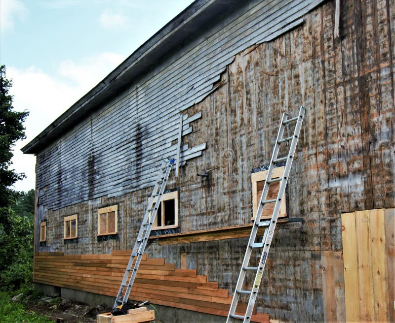 Replacing the Old, Gray Siding of Old Wooden Barn with New Brown Tan