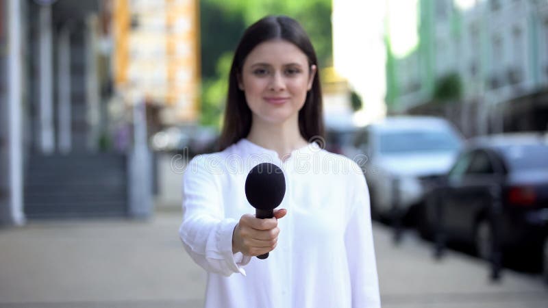 Reportera proponiendo micrófono, haciendo entrevistas en la calle, noticias diarias fotografía de archivo Reportera proponiendo micrófono, haciendo entrevistas en la calle, noticias diarias fotografía de archivo