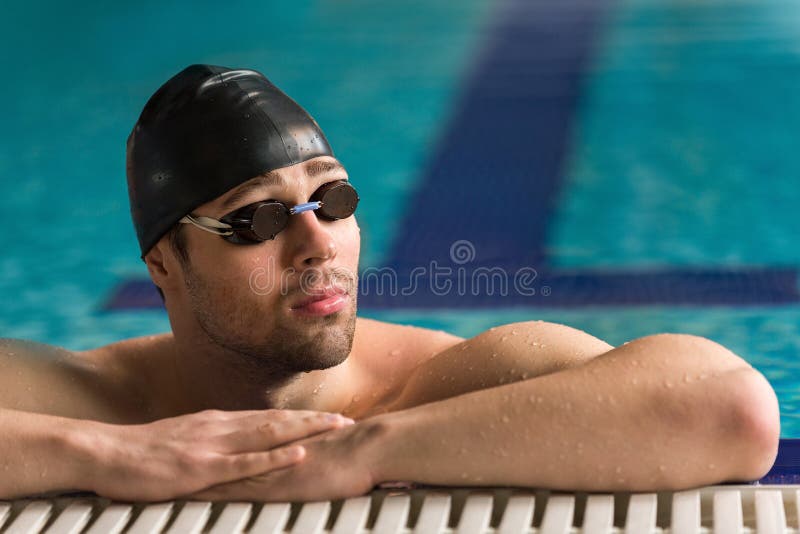 Repos de port de lunettes et de bonnet de bain de nageur masculin photographie stock libre de droits Repos de port de lunettes et de bonnet de bain de nageur masculin photographie stock libre de droits