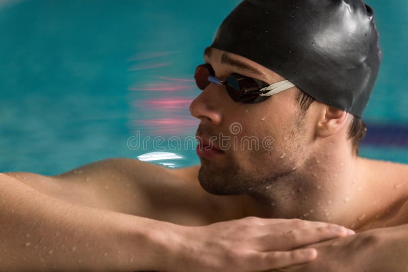 Repos de port de lunettes et de bonnet de bain de nageur masculin photographie stock Repos de port de lunettes et de bonnet de bain de nageur masculin photographie stock