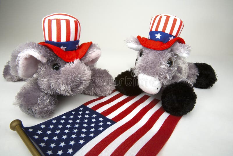 Elephant representing the Republican Party and Donkey representing the Democratic Party in red, white and blue Stars and Stripes hats facing nose to nose. Elephant representing the Republican Party and Donkey representing the Democratic Party in red, white and blue Stars and Stripes hats facing nose to nose.