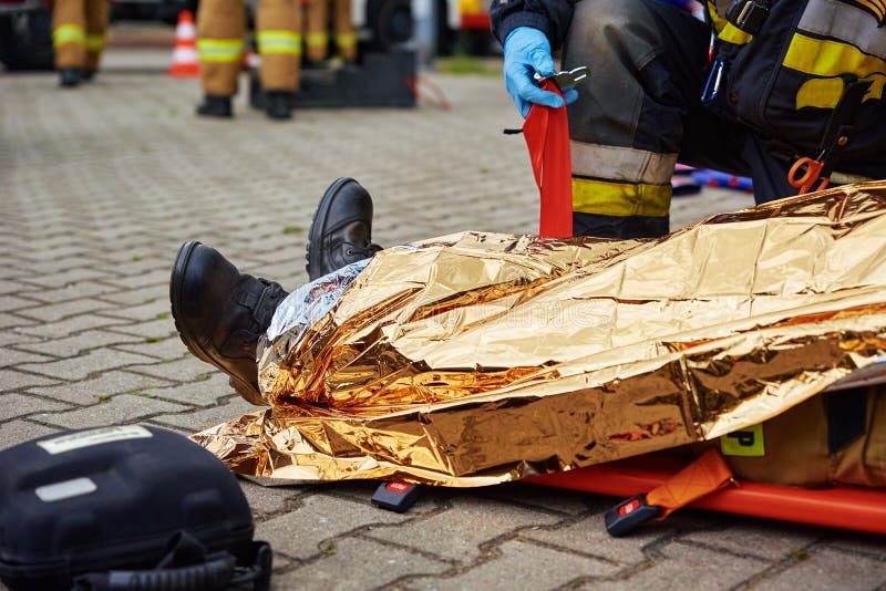 Rescuers provide first aid to the victim during a car accident. Person injured in the accident is lying on the road. Rescuers provide first aid to the victim during a car accident. Person injured in the accident is lying on the road