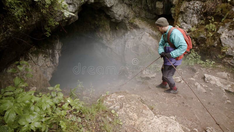 Resenären hamnar i grottan Lager Utforskaren med försäkringar går ned i en mörk grottgrop i bergart royaltyfri bild Resenären hamnar i grottan Lager Utforskaren med försäkringar går ned i en mörk grottgrop i bergart royaltyfri bild