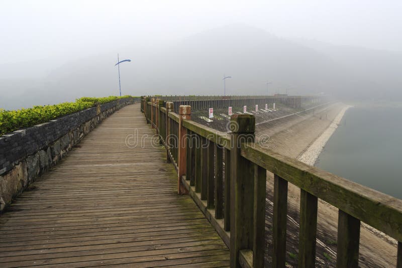 Reservatório da montanha de Tianzhu. Estrada de madeira da prancha do reservatório na névoa, cidade amoy da montanha do tianzhu, porcelana a palavra acima é proibida para nadar