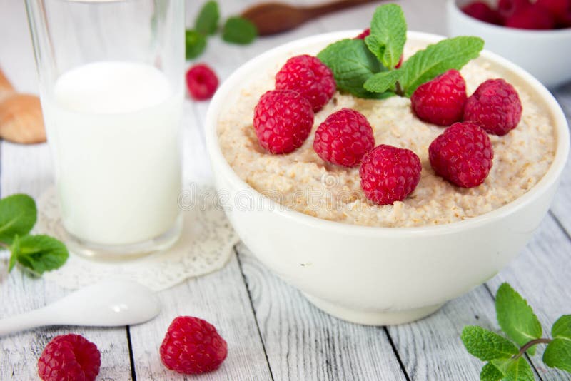 Resh delicious oatmeal with raspberries, next to a mug with milk stock photo