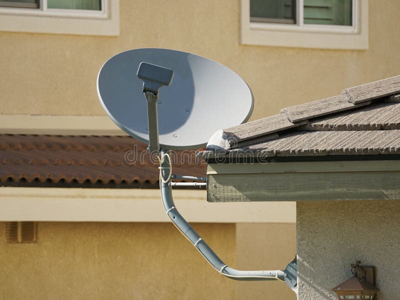 Residential satellite TV dish installed on eave of house