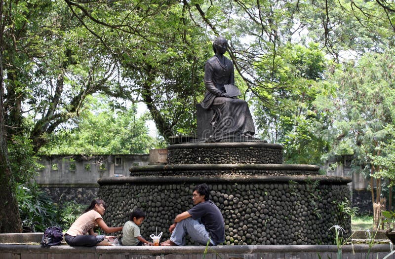 Residents relax in the park under a statue Partini Balaikambang