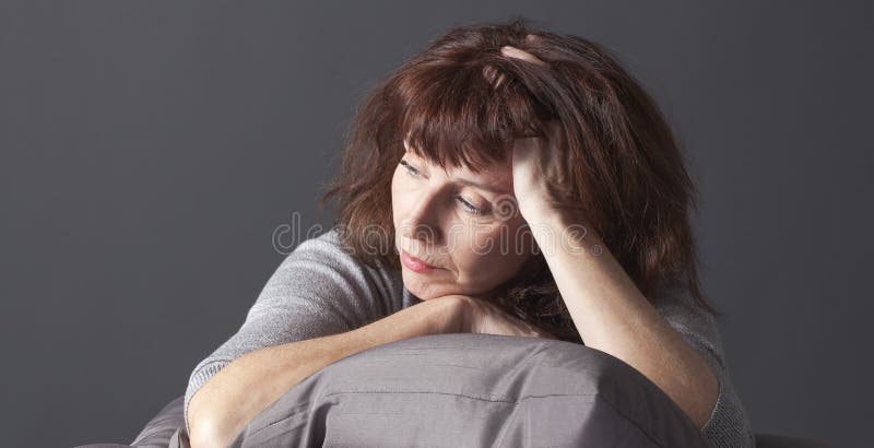 Müde Reife Frau ruht Ihr Gesicht und Ihre Hände legen sich auf Kissen für Komfort, während gesundheitliche Probleme.
