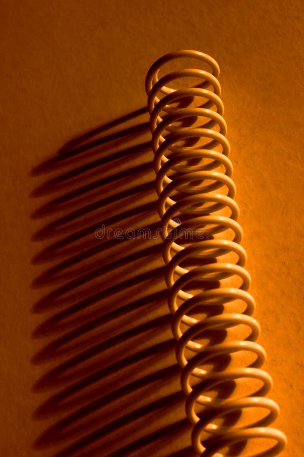 Metal spring on orange background with long shadows. Metal spring on orange background with long shadows