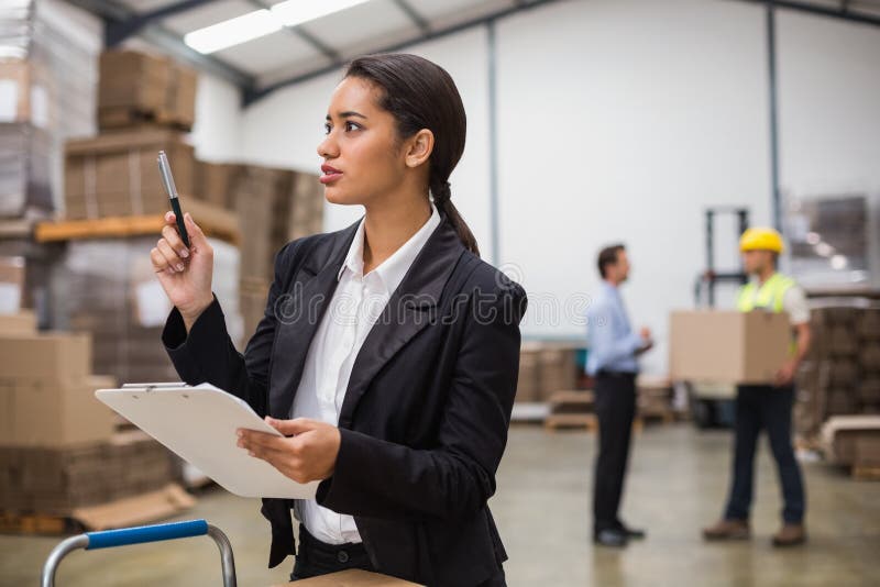 Responsabile grazioso del magazzino che controlla inventario fotografia stock Responsabile grazioso del magazzino che controlla inventario fotografia stock