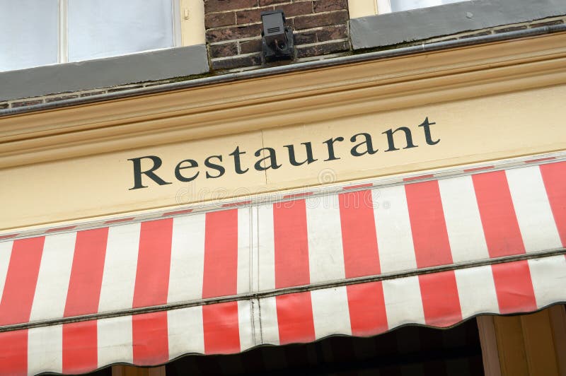 Restaurant sign and red white sunscreen on the facade of a building. Restaurant sign and red white sunscreen on the facade of a building