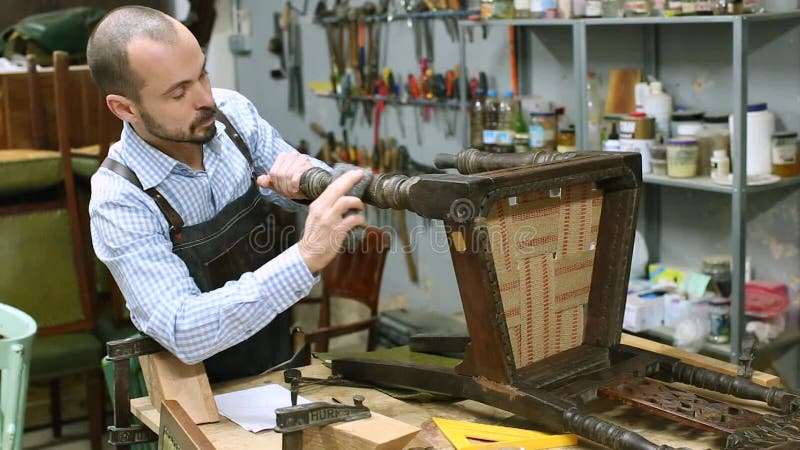 Restaurador de móveis reformando cadeira antiga em seu estúdio de madeira