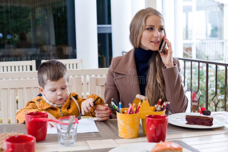 Restaurangmamma med sonen som talar på telefonen arkivfoton Restaurangmamma med sonen som talar på telefonen arkivfoton