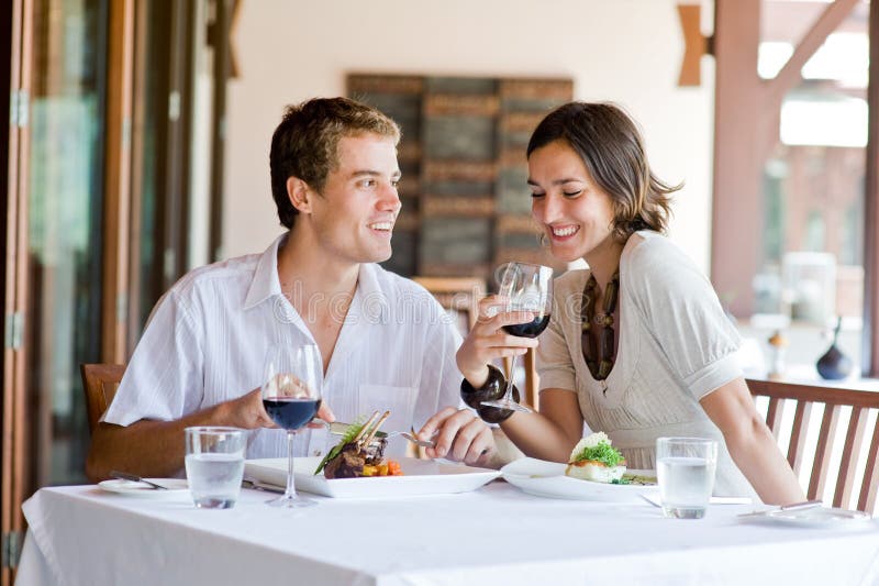 Una giovane coppia seduta a un tavolo in un ristorante all'aperto.
