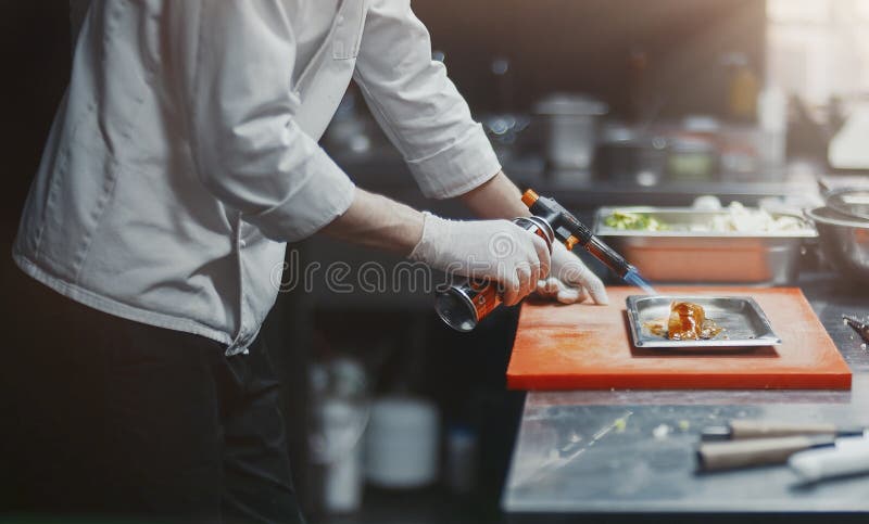 Restaurant Chef cook preparing salmon filet flambe in open kitchen. at restaurant. Restaurant Chef cook preparing salmon filet flambe in open kitchen. at restaurant