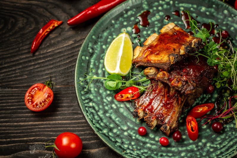 Restaurant food concept. pork ribs grilled with BBQ sauce. Tasty snack served with green seedlings on the plate. restaurant