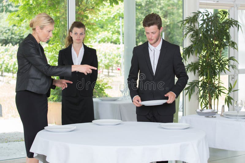 Restaurant manager showing how to set table stock images