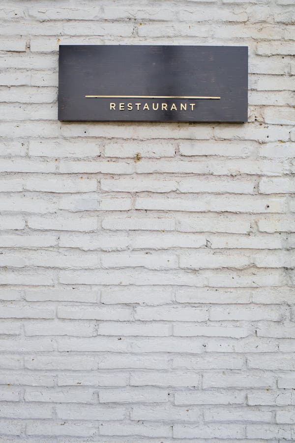 Restaurant sign on black marble board on white brick wall