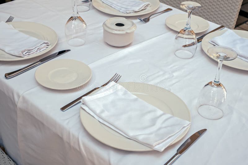 Restaurant table with empty plates napkins cutlery and glasses