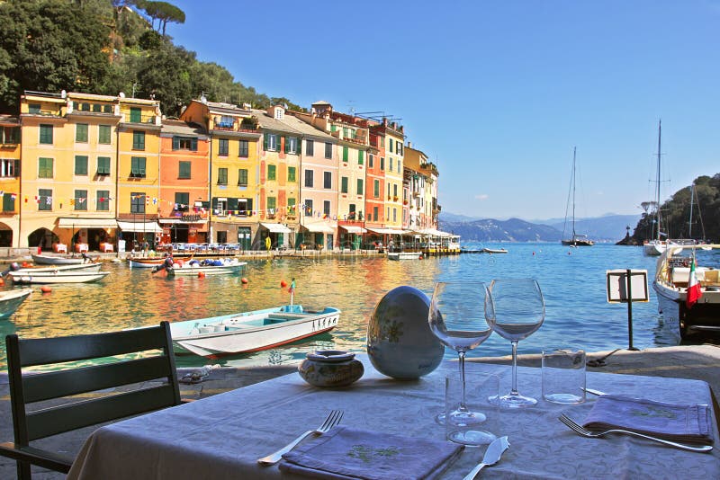 Outdoor restaurant in Portofino with beautiful view on multicolored houses and bay with yachts and boats on Ligurian Sea in Portofino, Italy. Outdoor restaurant in Portofino with beautiful view on multicolored houses and bay with yachts and boats on Ligurian Sea in Portofino, Italy.