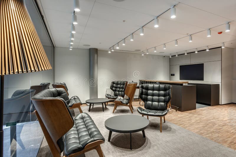 Resting lounge place with luxury armchairs in a modern office with glass walls and led lamps