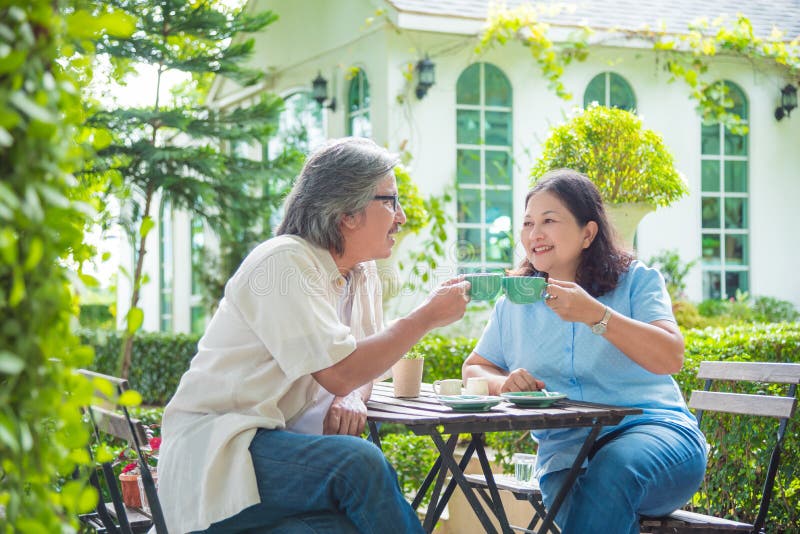 Retired couple sitting in garden and drinking coffee stock photo Retired couple sitting in garden and drinking coffee stock photo