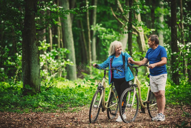 Retired couple walking with bikes in the forest. royalty free stock photography Retired couple walking with bikes in the forest. royalty free stock photography