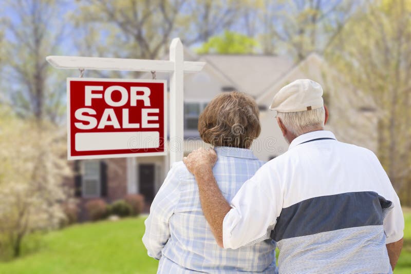 Happy Senior Couple Front of For Sale Real Estate Sign and House. Happy Senior Couple Front of For Sale Real Estate Sign and House.