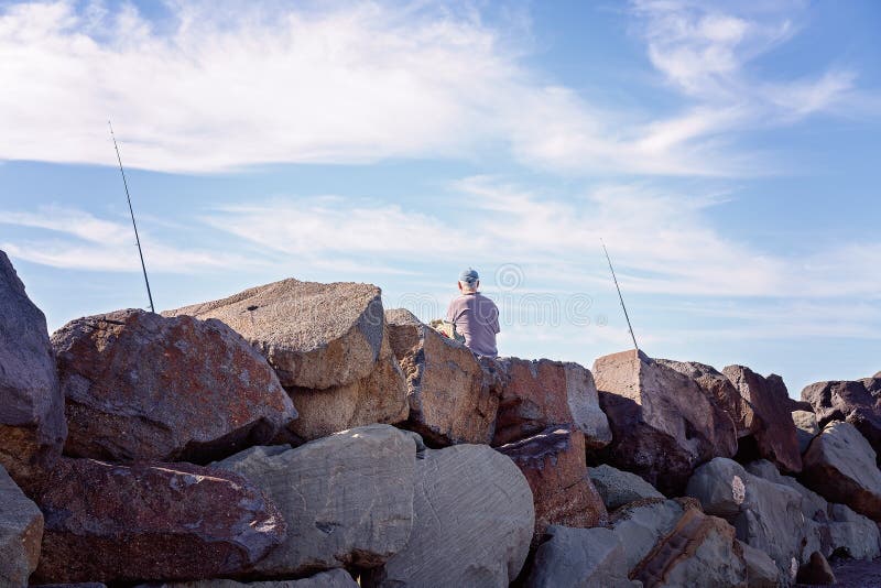 Retiree Fishing From Breakwater Rocks royalty free stock images Retiree Fishing From Breakwater Rocks royalty free stock images