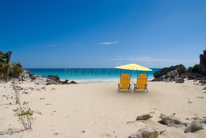 Tropical beach with sunshade and a pair of reclining chairs. Tropical beach with sunshade and a pair of reclining chairs