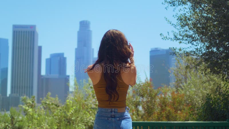Retour vue brunette touriste réalisation vidéo paysage urbain debout dans green park. clips vidéos