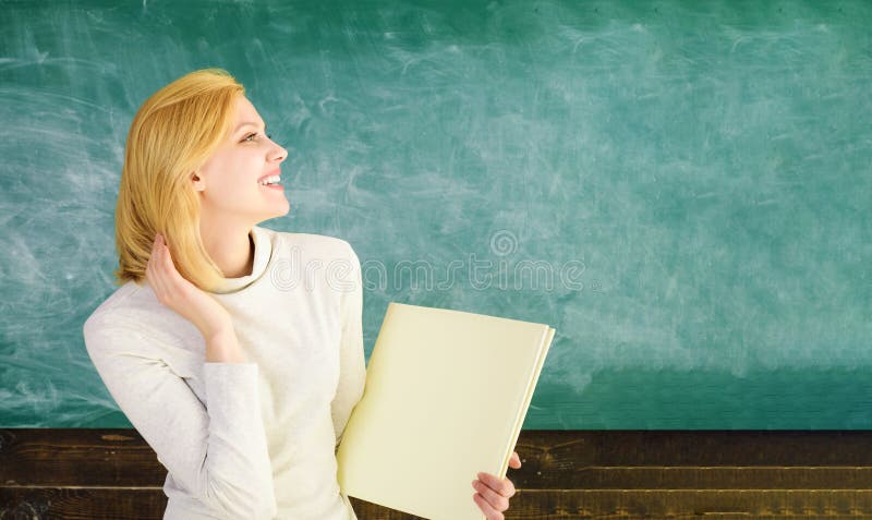 Retour à l'école. Enseignante avec dossier devant le tableau noir lors de la conférence à l'université. étudiante souriante avec photos libres de droits
