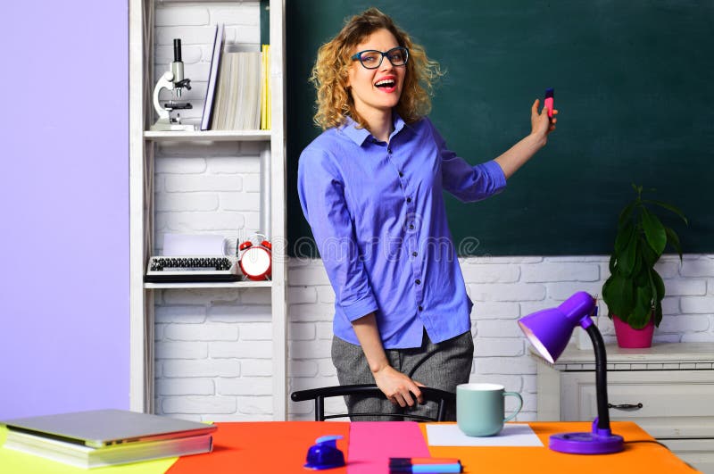 Retour à l'école. enseignante souriante dans des lunettes pointant vers le tableau de bord. étudiant heureux à l'université. enseignement. professeur d'université en classe pointant vers le tableau noir. lycée