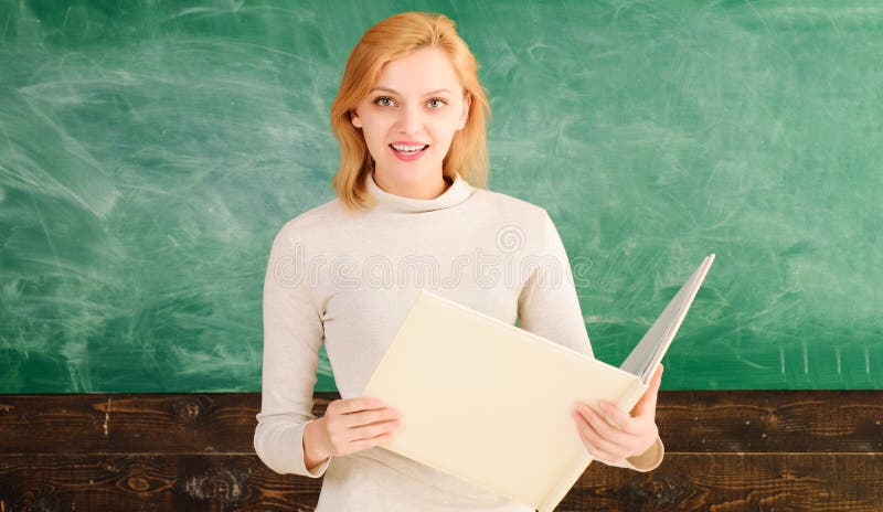 Retour à l'école. Portrait d'un jeune enseignant avec dossier devant le tableau noir lors de la conférence à l'université. Femme s image libre de droits