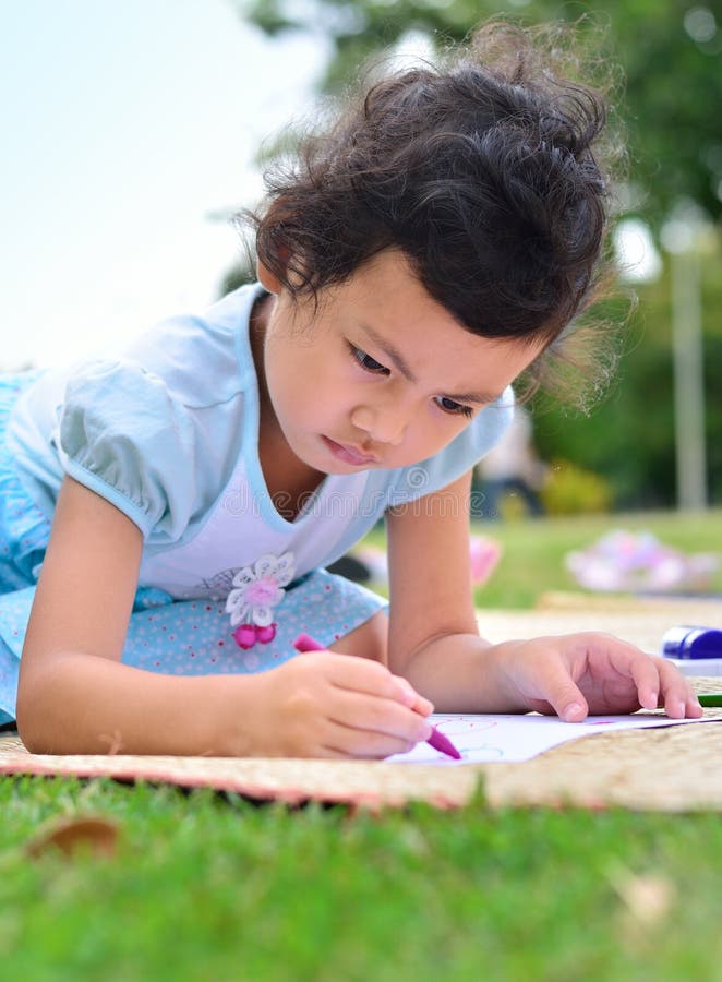 Retournant à l'école, au dessin de fille et à la peinture au-dessus de l'herbe verte photo stock Retournant à l'école, au dessin de fille et à la peinture au-dessus de l'herbe verte photo stock