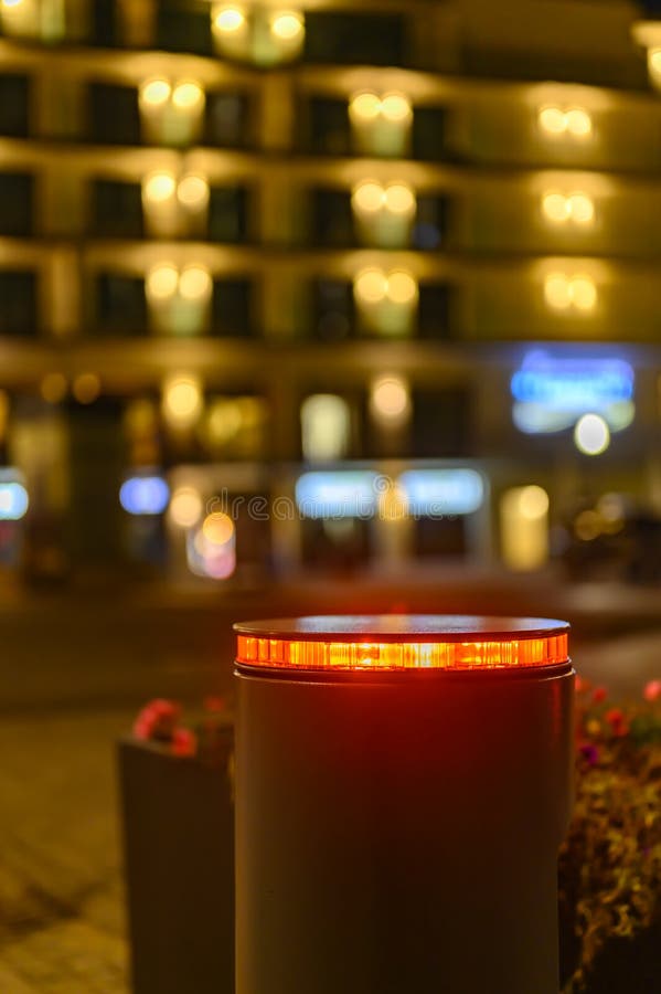Retractable bollard with a red warning light as a barrier to a pedestrian area at night in Bansin, Germany. In the background you