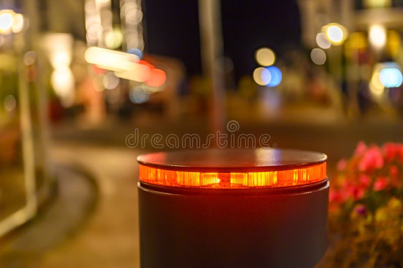 A retractable bollard with a red warning light as a barrier to a pedestrian area at night in Bansin, Germany.