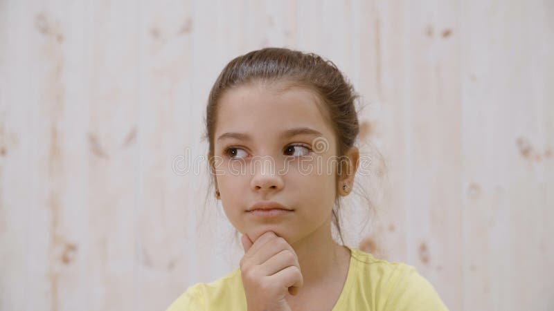 Retrair uma garota pensativa olhando para longe num fundo leve no estúdio Encerre a adolescente cara-a-cara Jovens