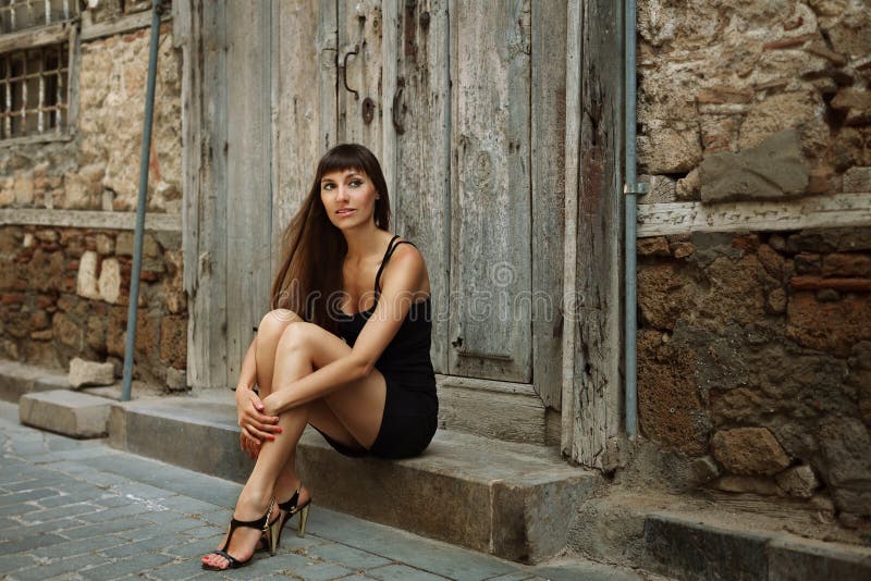 Retrato al aire libre de la forma de vida de la chica joven bonita, llevando en vestido negro en fondo urbano Imagen entonada col imagen de archivo Retrato al aire libre de la forma de vida de la chica joven bonita, llevando en vestido negro en fondo urbano Imagen entonada col imagen de archivo