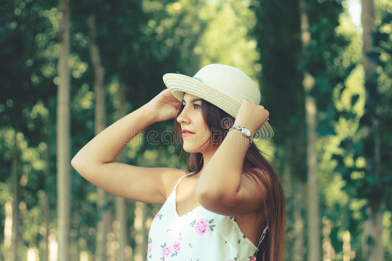Retrato al aire libre de un sombrero blanco del sol de la muchacha que lleva hermosa joven y de un vestido florido del verano fotos de archivo libres de regalías Retrato al aire libre de un sombrero blanco del sol de la muchacha que lleva hermosa joven y de un vestido florido del verano fotos de archivo libres de regalías