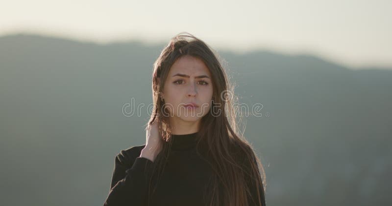 Retrato al aire libre de una joven caucásica joven sonriendo y mirando a la cámara en un día ventoso