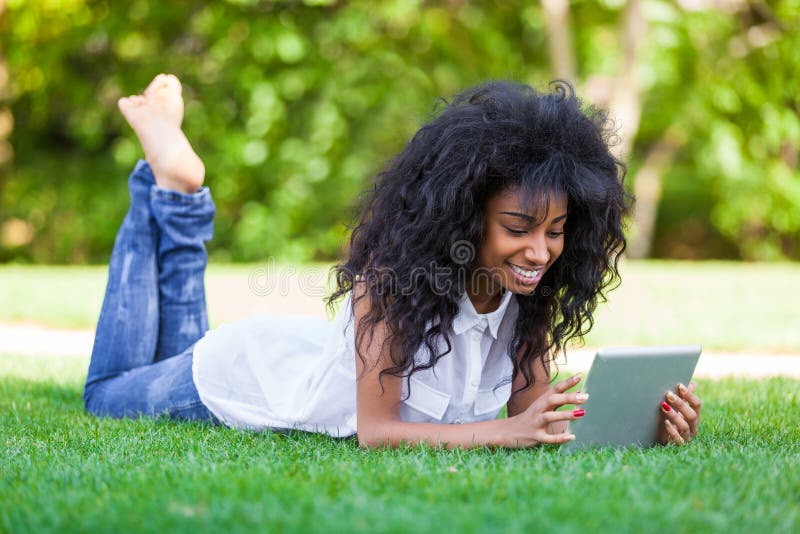 Retrato al aire libre de una muchacha negra adolescente que usa una tableta táctil imagenes de archivo Retrato al aire libre de una muchacha negra adolescente que usa una tableta táctil imagenes de archivo